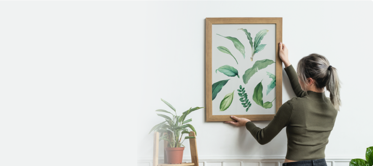 Woman fixing a large photo frame on a wall